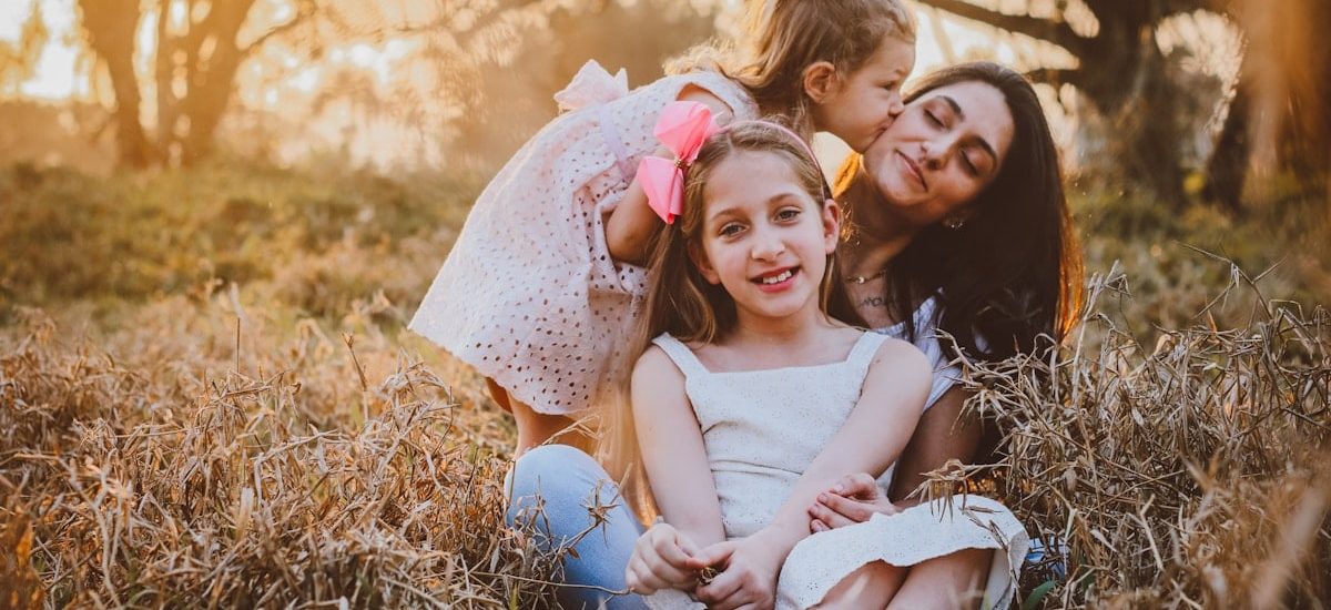 a family of three sitting in a field of tall grass