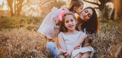 a family of three sitting in a field of tall grass