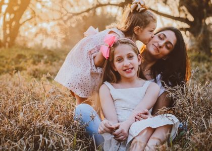 a family of three sitting in a field of tall grass